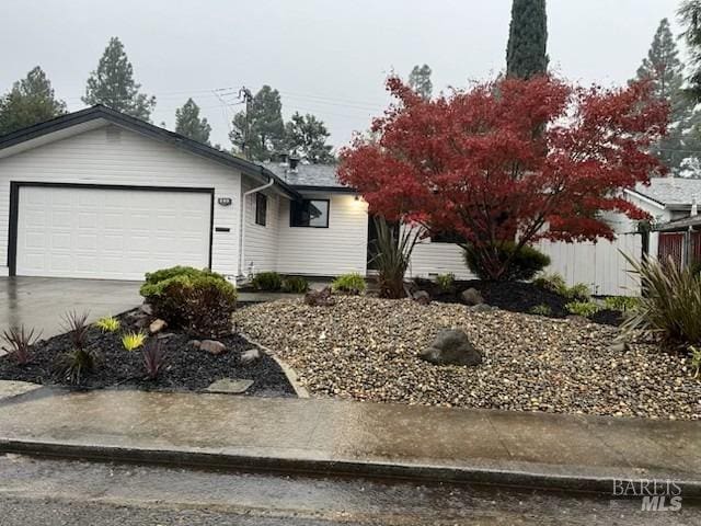 view of front facade featuring fence, concrete driveway, and an attached garage