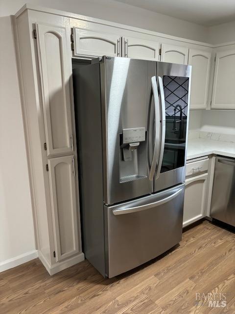 kitchen featuring appliances with stainless steel finishes, white cabinetry, light countertops, and light wood-style flooring