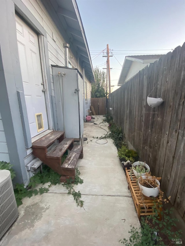 view of property exterior with central air condition unit, entry steps, and a fenced backyard