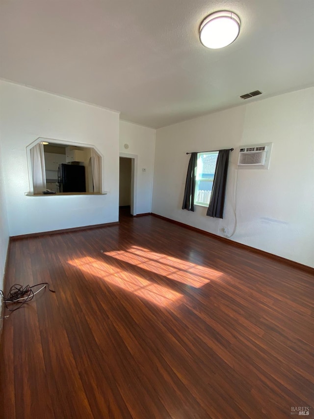 unfurnished living room with a wall unit AC and dark hardwood / wood-style floors