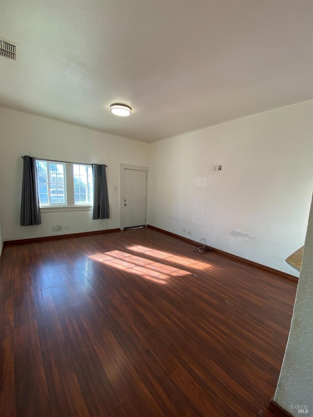 spare room with wood finished floors, baseboards, and visible vents