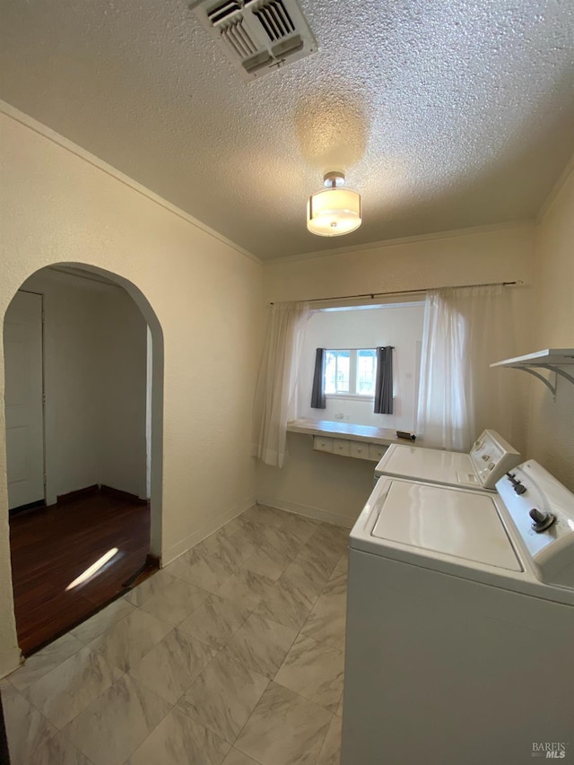 laundry room with arched walkways, separate washer and dryer, ornamental molding, visible vents, and marble finish floor