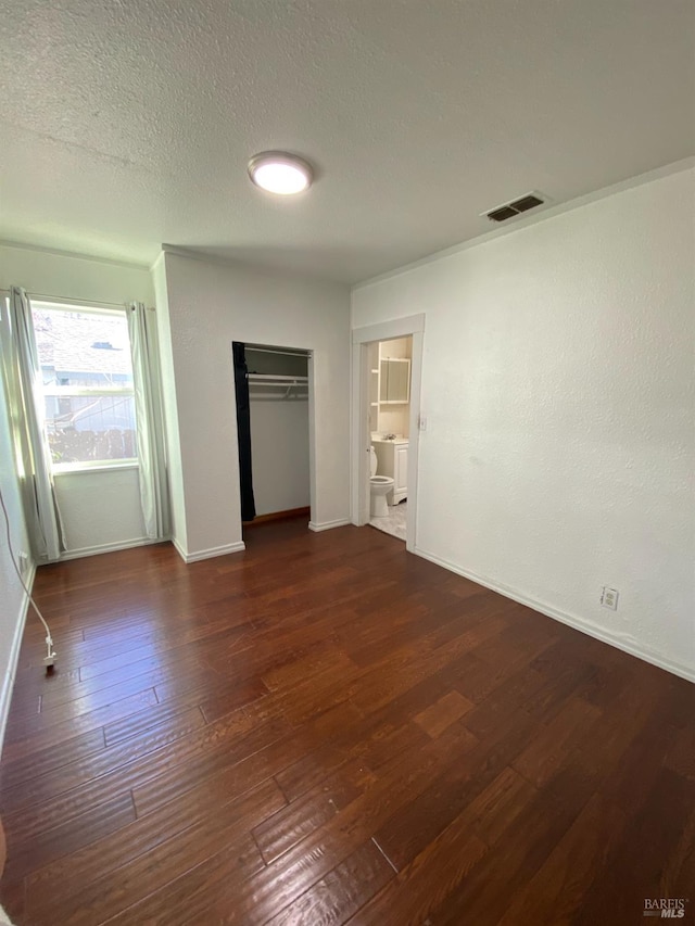 unfurnished bedroom with visible vents, baseboards, wood-type flooring, and a textured ceiling