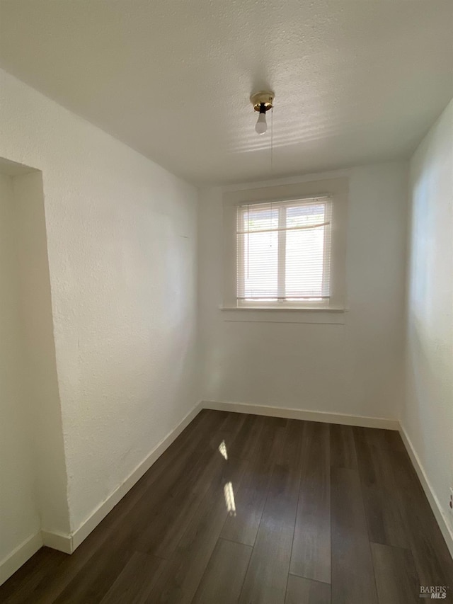 unfurnished room featuring a textured ceiling and dark wood-type flooring