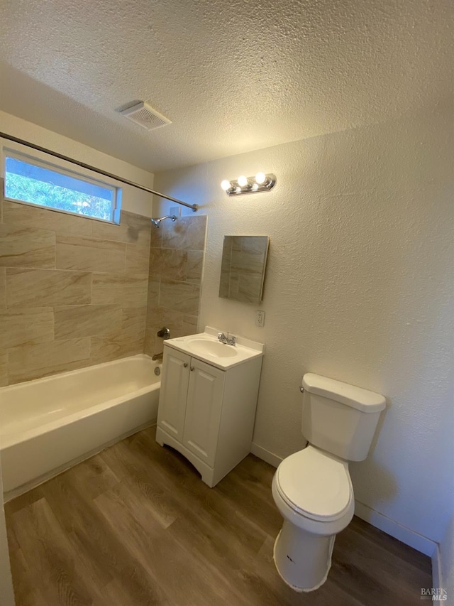 bathroom with a textured ceiling, vanity, visible vents, toilet, and wood finished floors