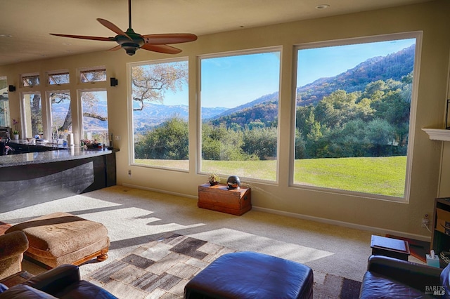 sunroom / solarium with a mountain view and ceiling fan