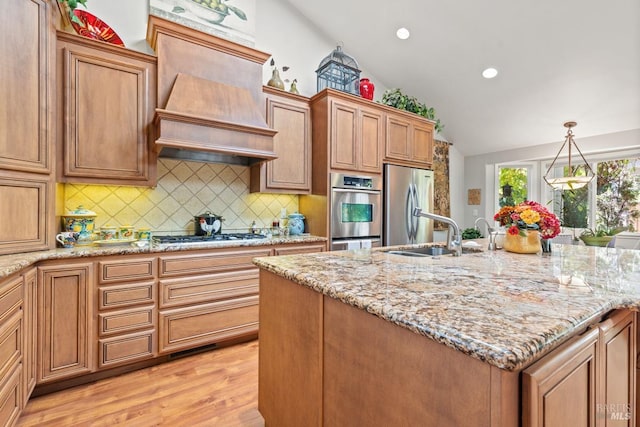 kitchen with lofted ceiling, sink, hanging light fixtures, light hardwood / wood-style flooring, and stainless steel appliances