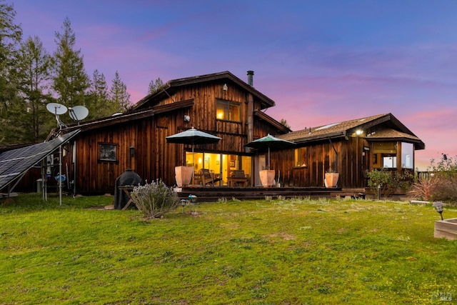 back house at dusk featuring a yard