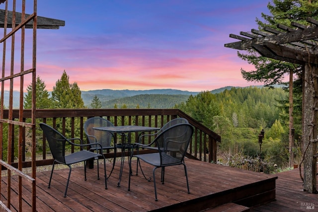 deck at dusk with a mountain view and a pergola