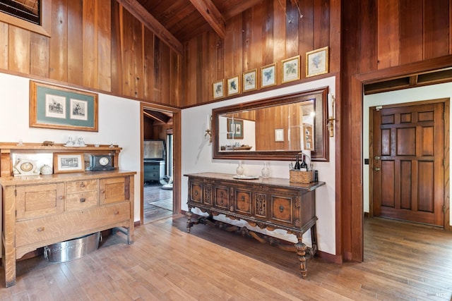 corridor with a towering ceiling, beamed ceiling, wooden ceiling, and hardwood / wood-style flooring