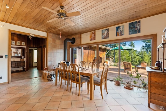 dining space with a wood stove, ceiling fan, light tile patterned floors, and wooden ceiling