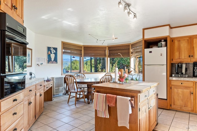 kitchen with a center island, white fridge, light tile patterned floors, and tasteful backsplash