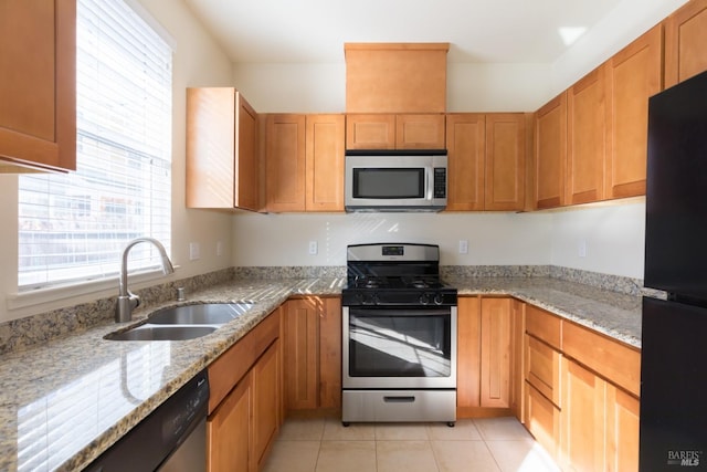 kitchen with light tile patterned flooring, light stone countertops, sink, and appliances with stainless steel finishes