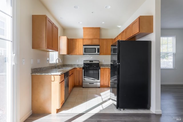 kitchen featuring light stone countertops, sink, light wood-type flooring, and appliances with stainless steel finishes