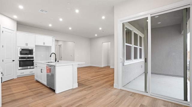 kitchen featuring white cabinetry, sink, light hardwood / wood-style floors, stainless steel appliances, and a center island with sink