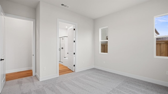 unfurnished bedroom with light colored carpet and ensuite bath