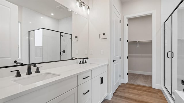 bathroom with an enclosed shower, vanity, and wood-type flooring