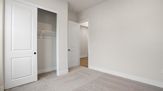 unfurnished bedroom featuring light carpet and a closet