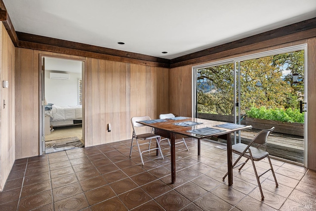 dining space with a wall unit AC, dark tile patterned floors, and wooden walls