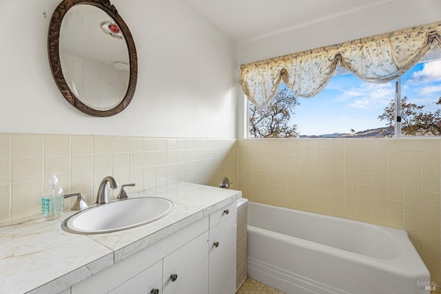 bathroom with a tub to relax in, vanity, and tile walls