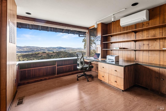 unfurnished office featuring dark hardwood / wood-style flooring, track lighting, wooden walls, an AC wall unit, and a mountain view