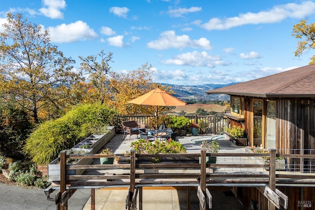 wooden deck with a mountain view and a patio