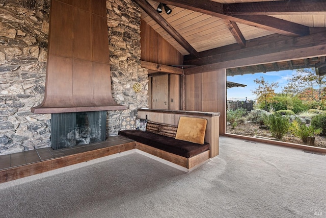 interior space with carpet flooring, beam ceiling, a fireplace, and wooden ceiling