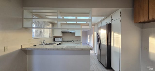 kitchen with white cabinets, stainless steel fridge with ice dispenser, light stone countertops, and sink