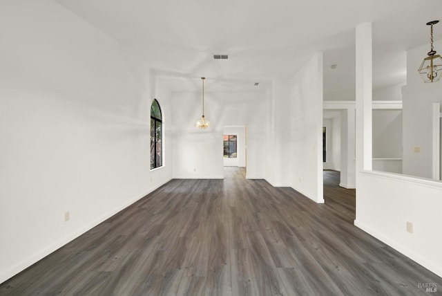 unfurnished living room with dark hardwood / wood-style floors, vaulted ceiling, and a chandelier