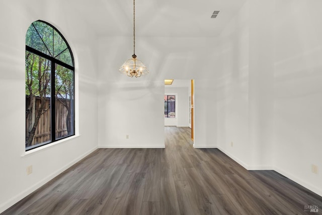 unfurnished dining area with dark wood-type flooring, a high ceiling, and a chandelier