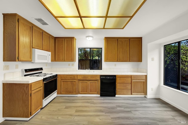 kitchen featuring light hardwood / wood-style flooring, a healthy amount of sunlight, and white appliances