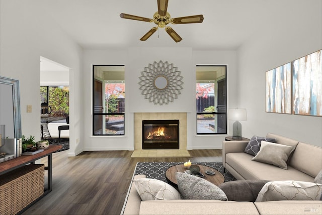 living room featuring a tiled fireplace, ceiling fan, and dark hardwood / wood-style floors