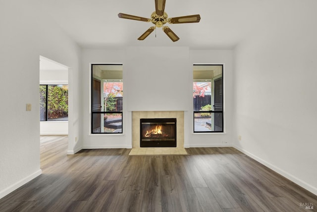 unfurnished living room featuring a fireplace, dark hardwood / wood-style floors, and ceiling fan