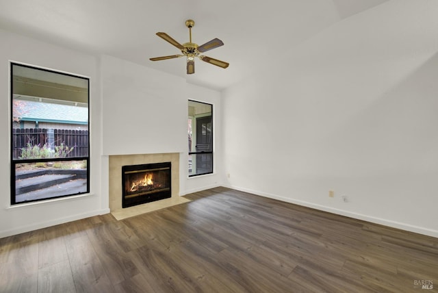 unfurnished living room with a fireplace, ceiling fan, and dark wood-type flooring