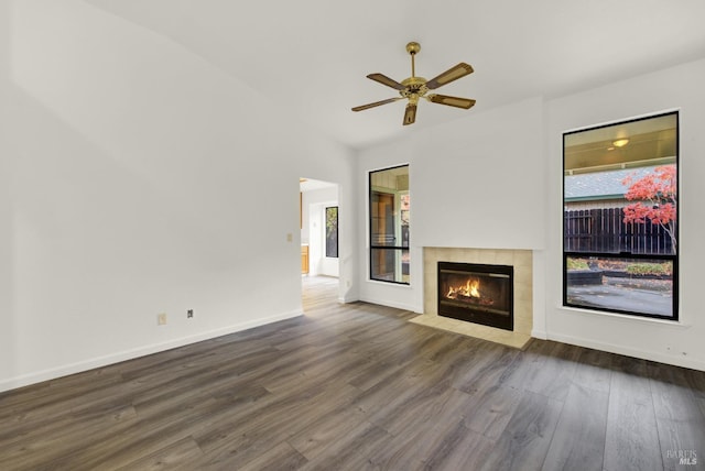 unfurnished living room featuring dark hardwood / wood-style floors, ceiling fan, lofted ceiling, and a tiled fireplace