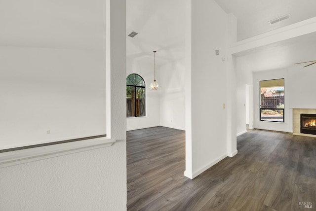 interior space featuring dark wood-type flooring, a high ceiling, and an inviting chandelier