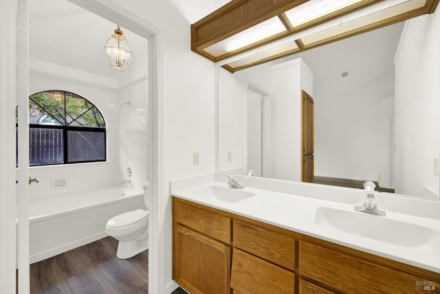 full bathroom featuring a notable chandelier, bathing tub / shower combination, hardwood / wood-style floors, toilet, and vanity