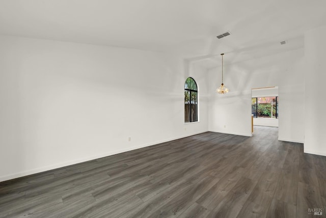 spare room featuring dark hardwood / wood-style flooring, lofted ceiling, and an inviting chandelier