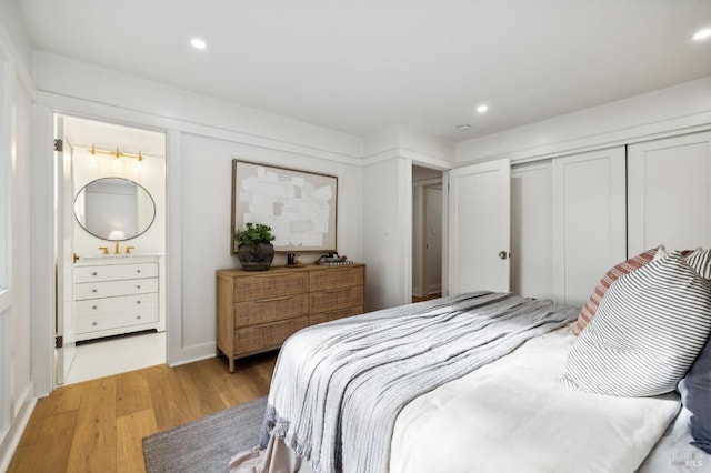 bedroom with light wood-type flooring and connected bathroom