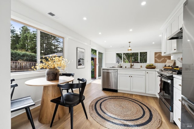 kitchen with pendant lighting, stainless steel appliances, white cabinetry, and plenty of natural light