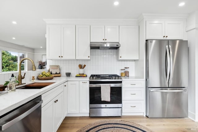 kitchen featuring white cabinetry, sink, stainless steel appliances, light hardwood / wood-style flooring, and decorative backsplash