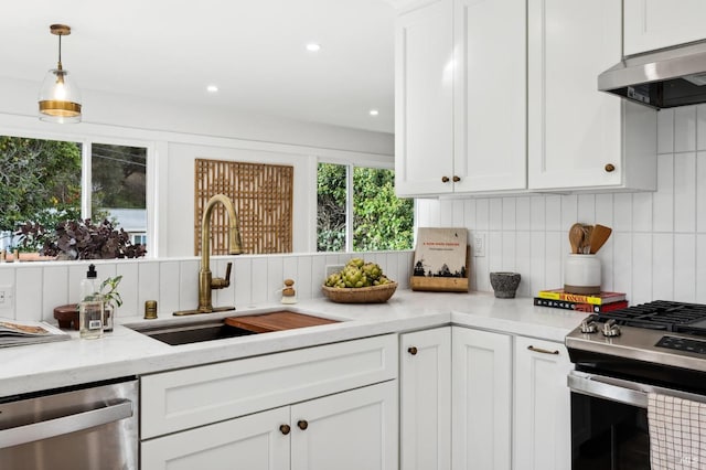 kitchen featuring white cabinetry, sink, range hood, backsplash, and appliances with stainless steel finishes