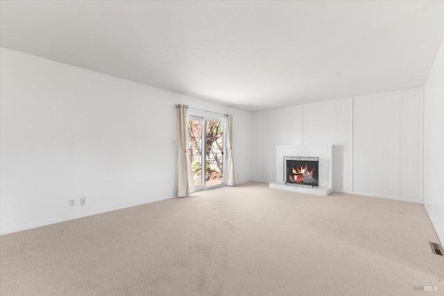 unfurnished living room with visible vents, light colored carpet, and a brick fireplace