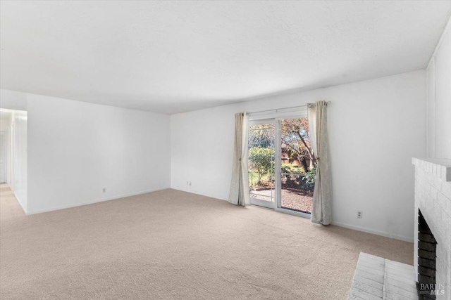 unfurnished living room featuring light carpet, a textured ceiling, and a brick fireplace