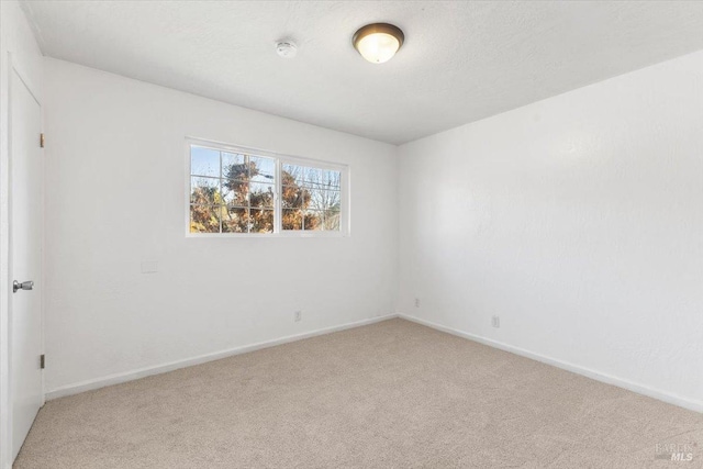 unfurnished room featuring baseboards, light carpet, and a textured ceiling