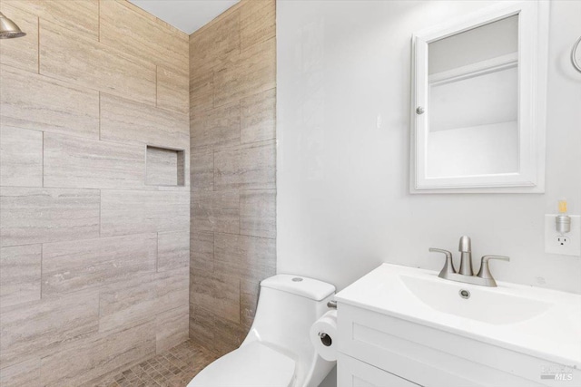 bathroom with vanity, toilet, and a tile shower