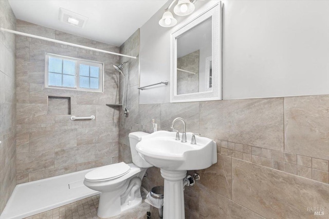 bathroom with toilet, visible vents, tiled shower, and tile walls