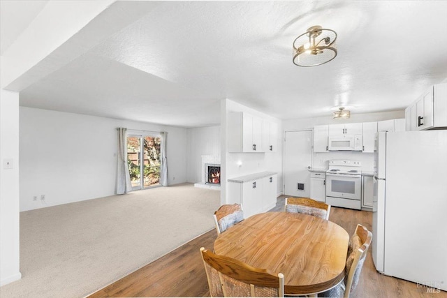 dining room with light colored carpet, a fireplace, and light wood-type flooring
