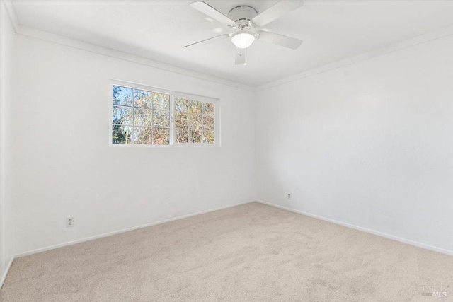 carpeted empty room featuring baseboards, a ceiling fan, and ornamental molding