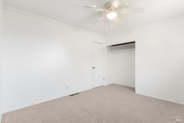 unfurnished bedroom featuring visible vents, ornamental molding, a ceiling fan, a closet, and carpet floors